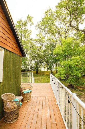 A wooden deck with wicker furniture and a white railing.