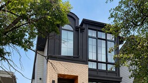 A modern two-story house with a brick facade, large windows, and a front entrance with a staircase.
