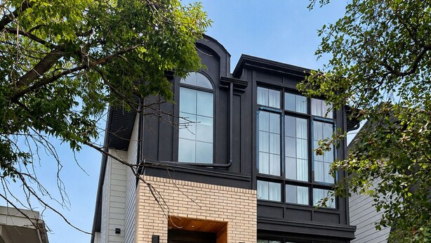 Een modern huis met twee verdiepingen, een bakstenen gevel, grote ramen en een entree met een trap.