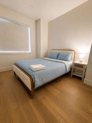A bedroom with a bed, nightstand, and a window with blinds. - Haven on 54th | Modern Luxury Retreat | 3BR 2.5BA Sleeps 6 (Calgary)