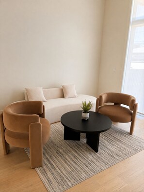 A modern living room with a sofa, two armchairs, a coffee table, and a potted plant. - Haven on 54th | Modern Luxury Retreat | 3BR 2.5BA Sleeps 6 (Calgary)