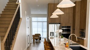 Een moderne keuken met een marmeren aanrechtblad, houten kastjes en hanglampen.
