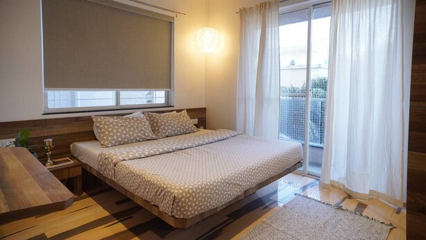 A bedroom with a bed, bedside table, and a view of the outdoors through a window.