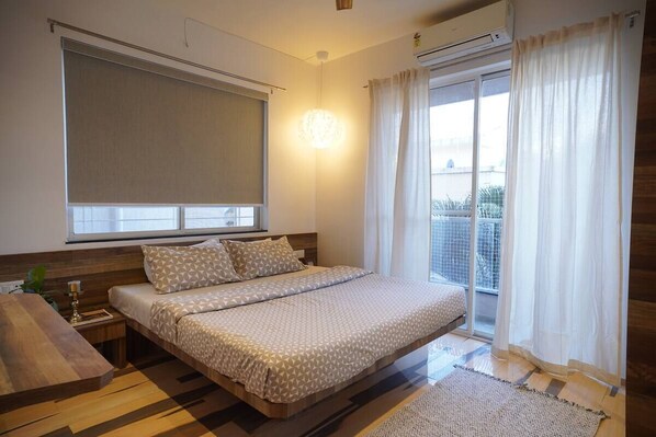 A bedroom with a bed, bedside table, and a view of the outdoors through a window.