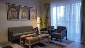 A living room with a sofa, armchair, coffee table, and a large window with curtains.