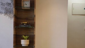 A wooden cabinet with a clock, shelves with books, and a potted plant.
