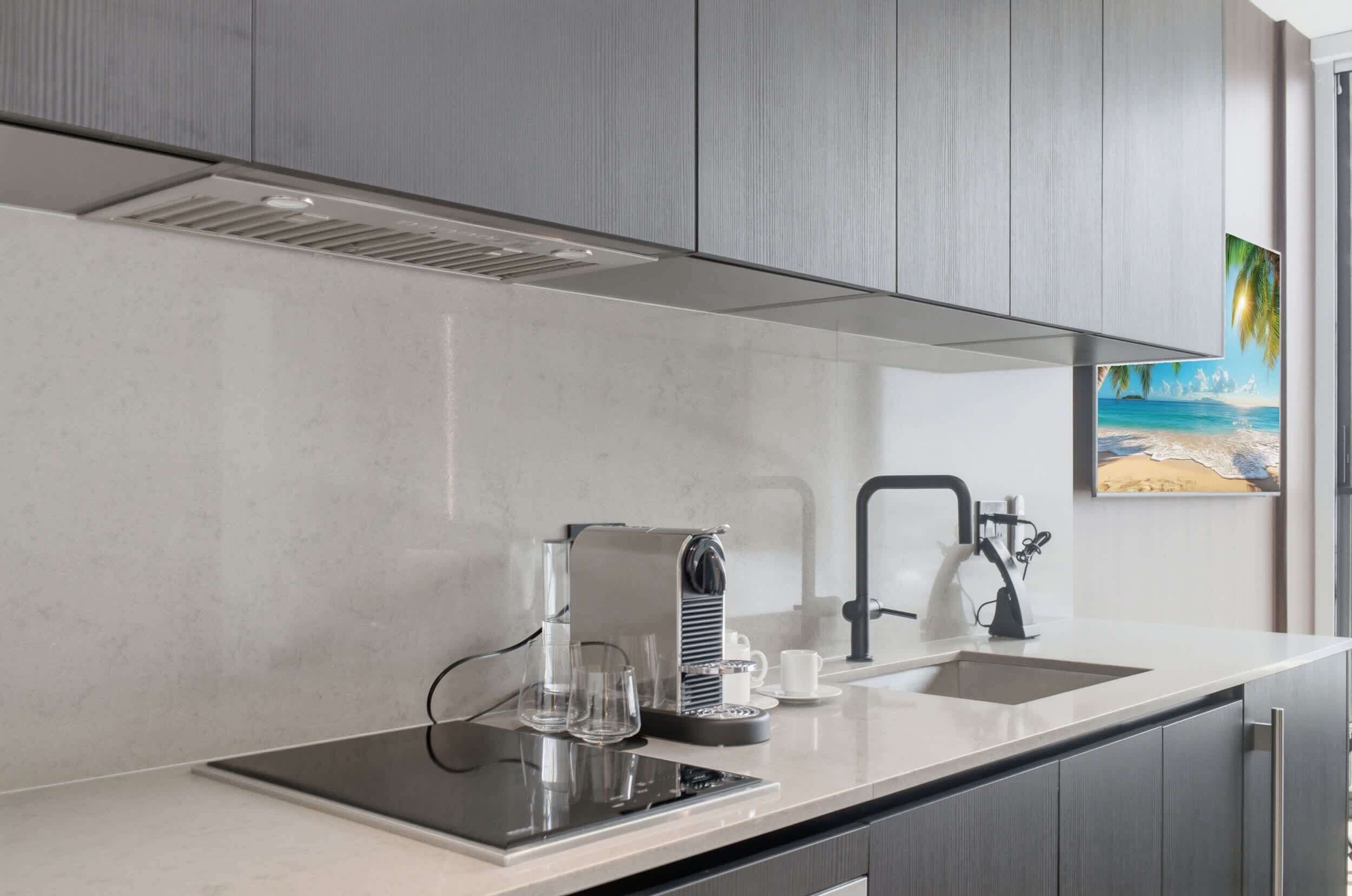 A modern kitchen with a built-in stove, a coffee maker, and a sink.