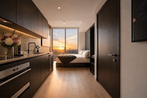 A modern kitchen with a built-in oven, a dining area with a table and chairs, and a large window with a city view. - Elite E11EVEN Studio with Rooftop Pool & Resort Gym (Miami)
