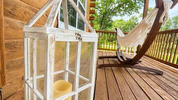 A wooden porch with a hammock and a white lantern.