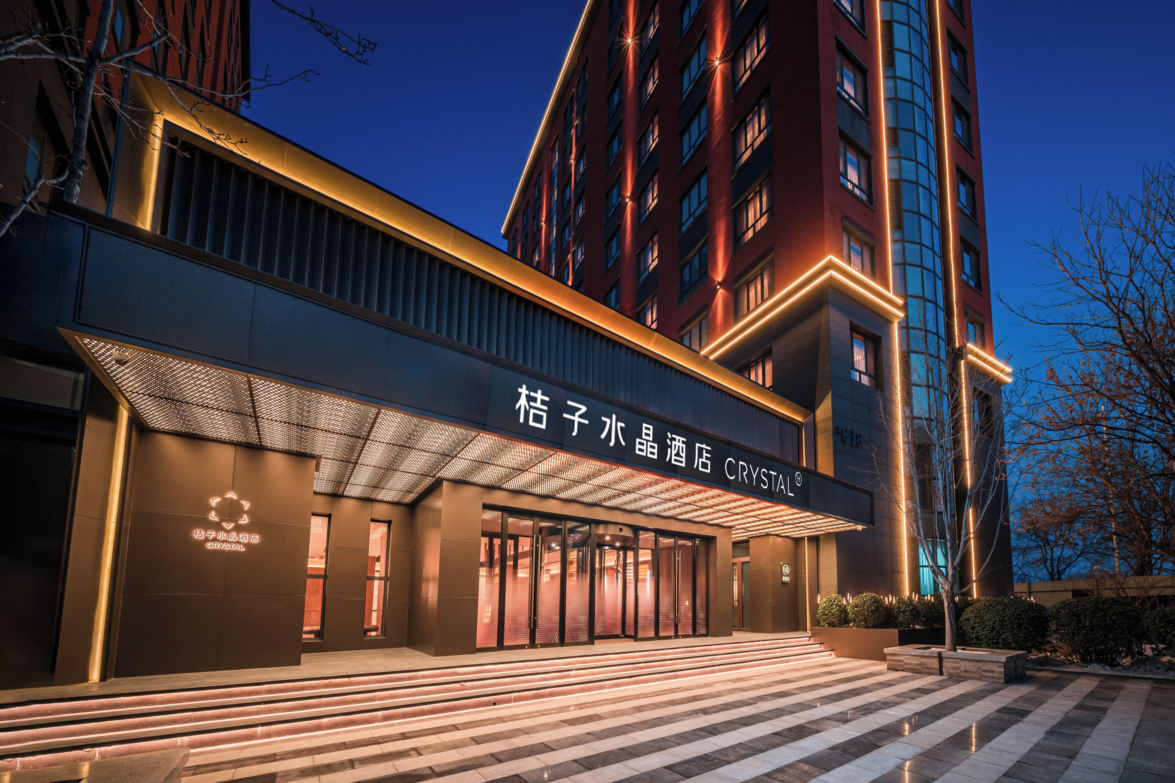 A hotel entrance with a modern design, featuring a large glass facade and a prominent signage.