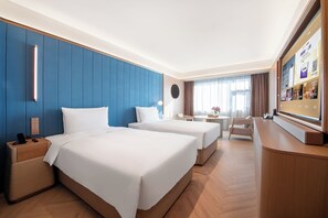 Habitación de hotel con dos camas, un escritorio, una silla y un televisor.