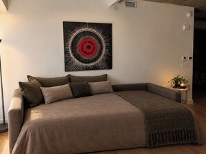 A modern bedroom with a large bed, a wall-mounted abstract artwork, and a bedside table with a plant. - The Panorama · Sleeps 9 · 2 baths · EV parking (Québec City)