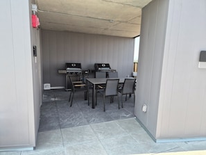 An outdoor patio area with two barbecue grills, a table, and four chairs. - The Panorama · Sleeps 9 · 2 baths · EV parking (Québec City)