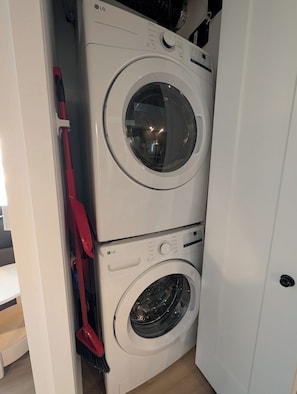 A stacked washer and dryer unit with a red mop leaning against it. - The Panorama · Sleeps 9 · 2 baths · EV parking (Québec City)
