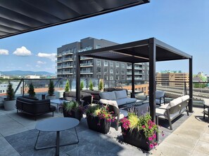 A rooftop terrace with outdoor seating, potted plants, and a view of a cityscape. - The Zenith · Sleeps 8 · 11th fl · EV parking (Québec City)