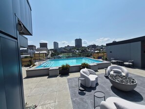 A rooftop pool with a cityscape view, outdoor seating, and a clear sky. - The Zenith · Sleeps 8 · 11th fl · EV parking (Québec City)