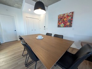 Ein Konferenzraum mit Holztisch, schwarzen Stühlen, einer weißen Tür und einem farbenfrohen abstrakten Gemälde an der Wand.