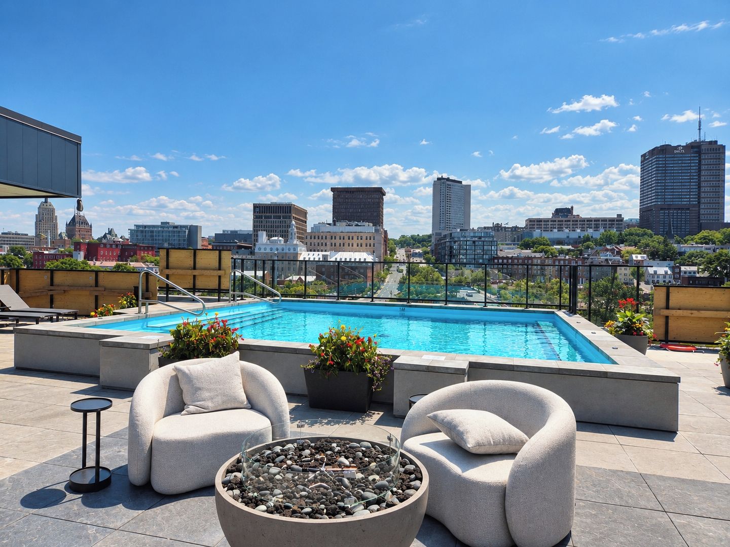 Un espace piscine aménagé sur le toit, offrant une vue sur la ville, avec des chaises longues et un foyer extérieur.