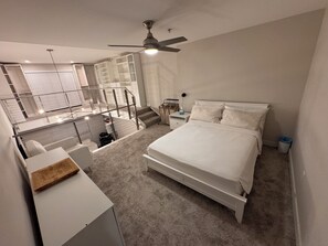 Ein Schlafzimmer mit einem Bett, einem Schreibtisch, einem Deckenventilator und einer Treppe, die zu einer oberen Ebene führt.