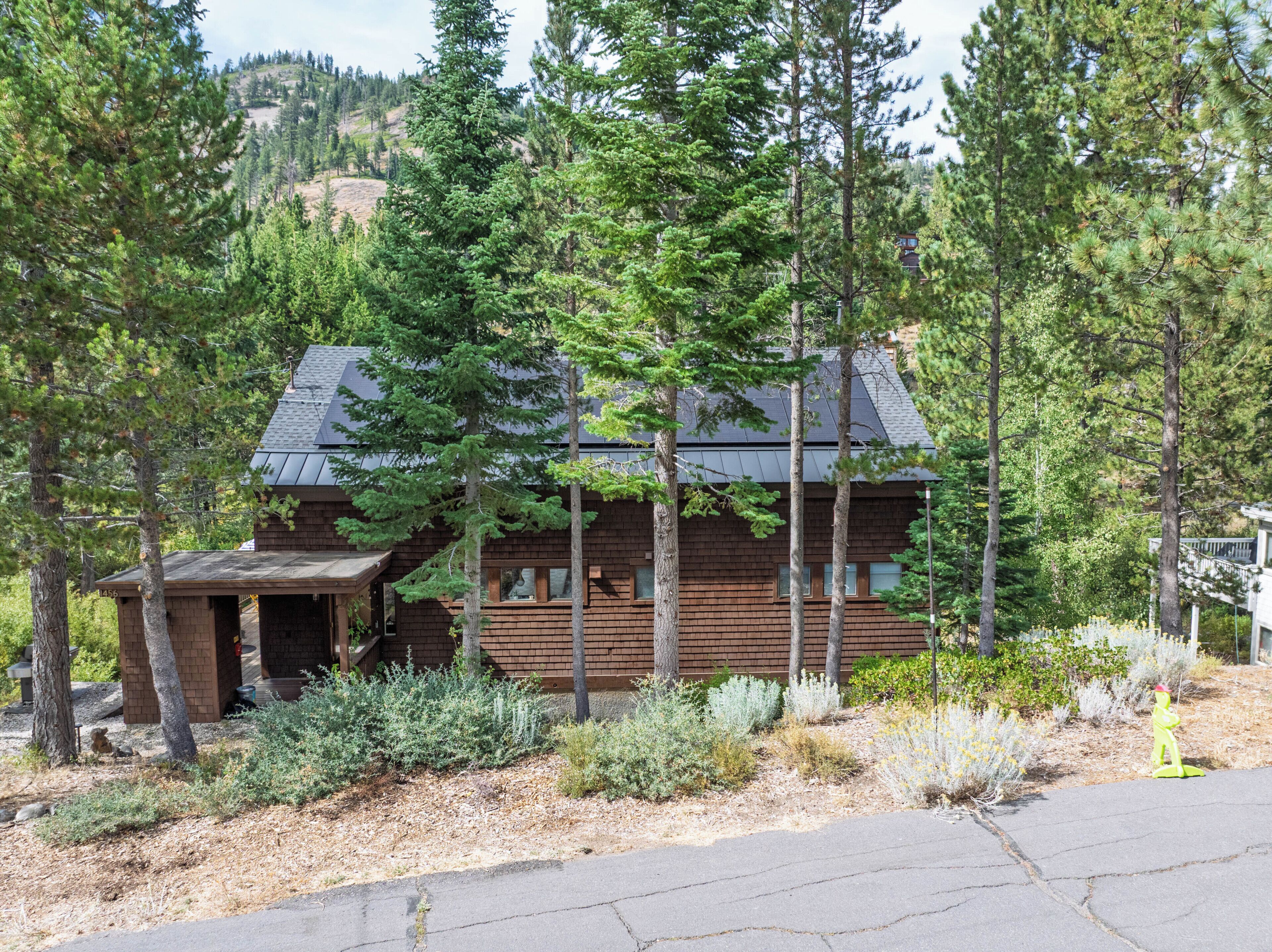 A cabin with a wooden exterior, surrounded by tall trees and a clear sky.