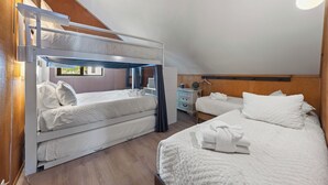 Ein Zimmer mit Etagenbetten, einem Nachttisch, einer Kommode und einer Pendelleuchte.