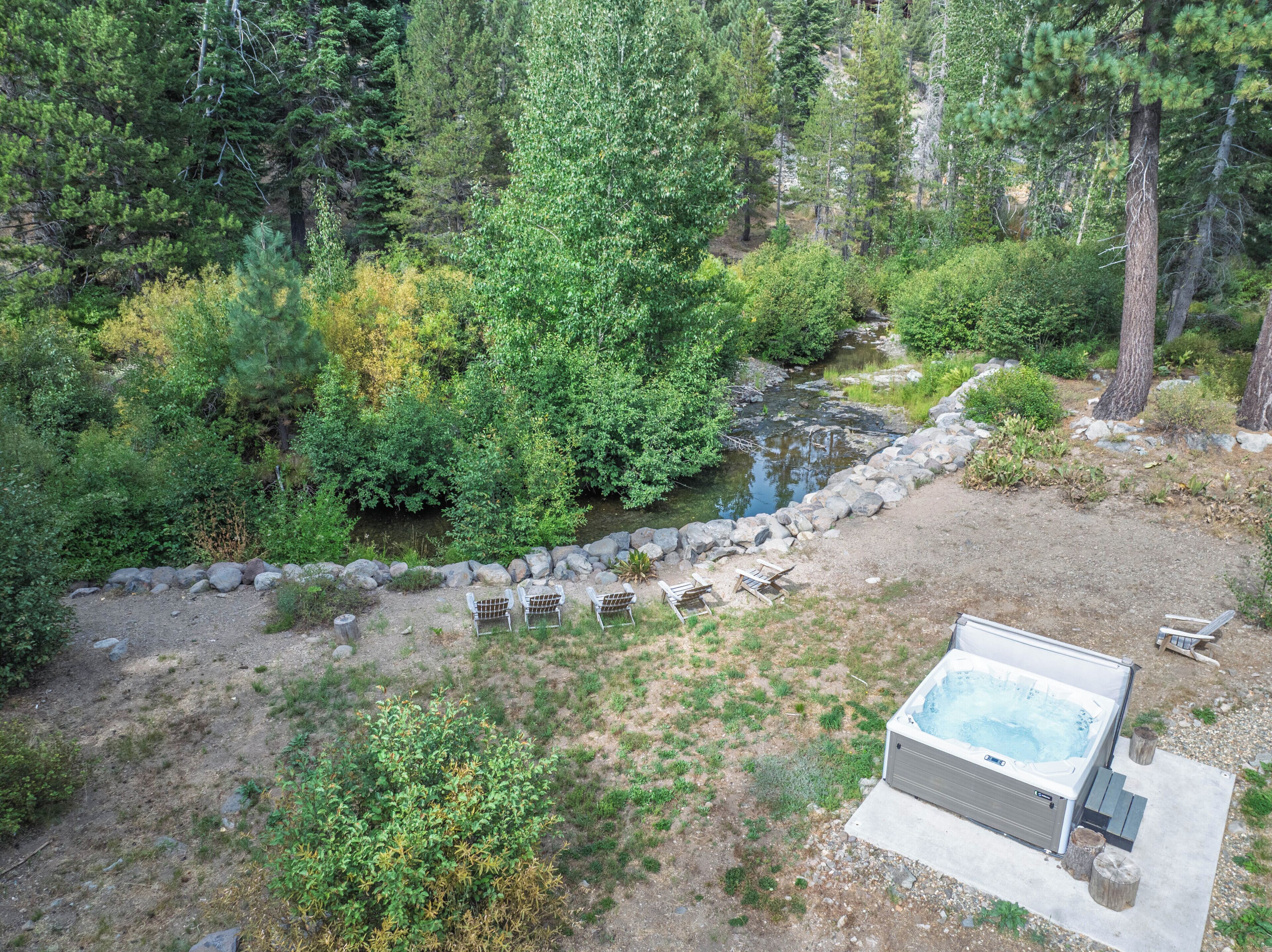 A hot tub surrounded by a natural landscape with a rocky path and dense greenery.