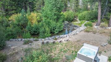 A hot tub surrounded by a natural landscape with a rocky path and dense greenery.