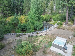 A hot tub surrounded by a natural landscape with a rocky path and dense greenery.