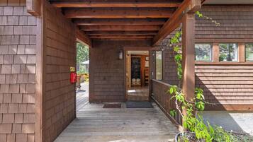 A wooden covered porch leading to a building with a door and windows.