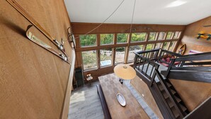 Ein Holzkamin mit einem großen Fenster, einer Hängeleuchte und einer Treppe.
