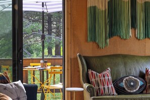 A room with a green leather sofa, a yellow chair, and a table with plates and cutlery.