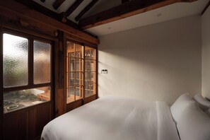 A bedroom with a large window, wooden beams on the ceiling, and a bed with white bedding. - The Prima Hotel Hanok Dambakjae Gyedong (Seoul)