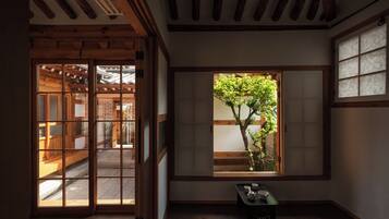 A traditional Japanese room with sliding doors, a window with a view of a tree, and a small table with tea set.