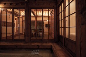Quarto tradicional japonês com portas de correr, piso de esteira de tatame e um banco de madeira baixo.