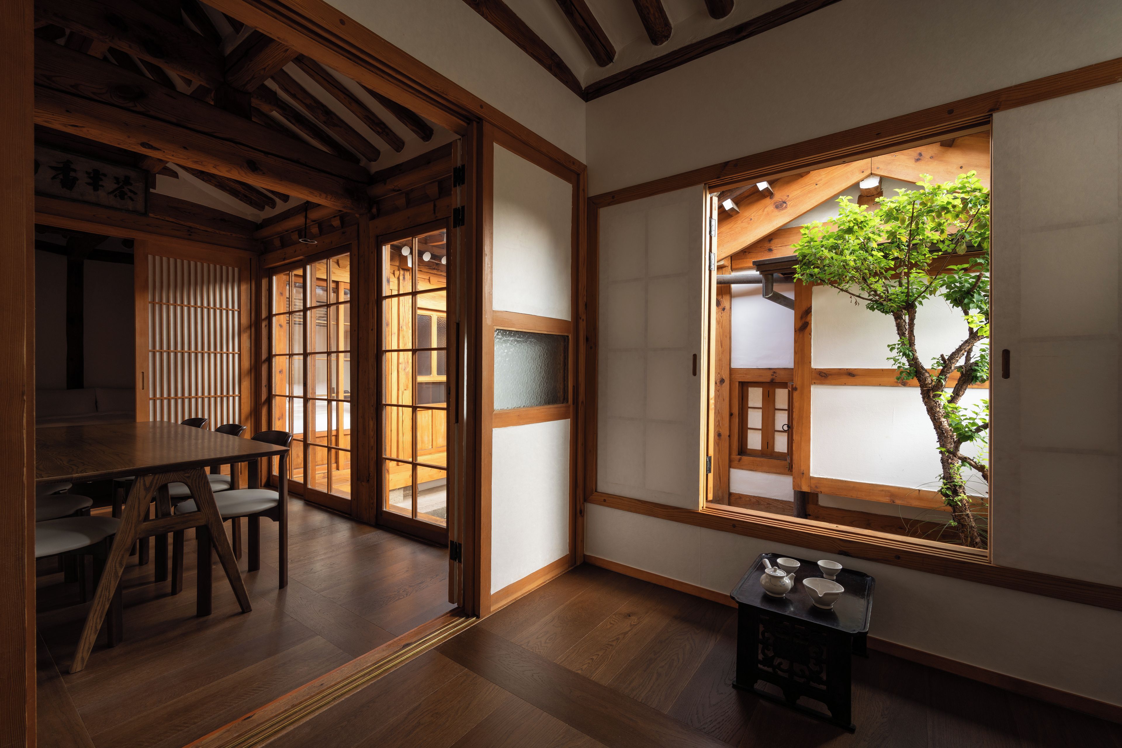 A traditional Japanese room with tatami flooring, sliding doors, and a view of a tree through a window.