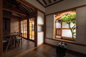 A traditional Japanese room with tatami flooring, sliding doors, and a view of a tree through a window.