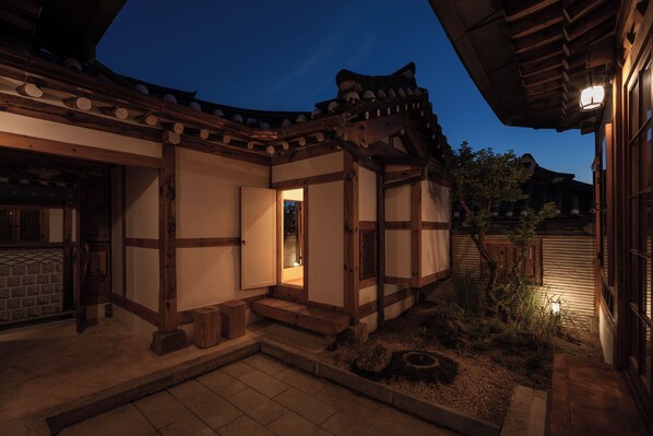 A traditional wooden building with a tiled entrance and a small garden area.