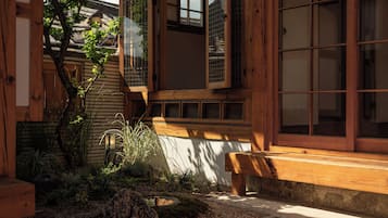 Un edificio de madera tradicional con un banco de madera, un sendero de piedra y un pequeño jardín con plantas y una roca.