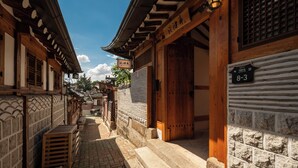 Un callejón tradicional coreano con edificios de madera, paredes de azulejos y un letrero que indica la habitación número 8-3.