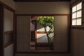 A traditional Japanese room with tatami flooring, a shoji screen door, and a view of a tree outside. - The Prima Hotel Hanok Dambakjae Gyedong (Seoul)
