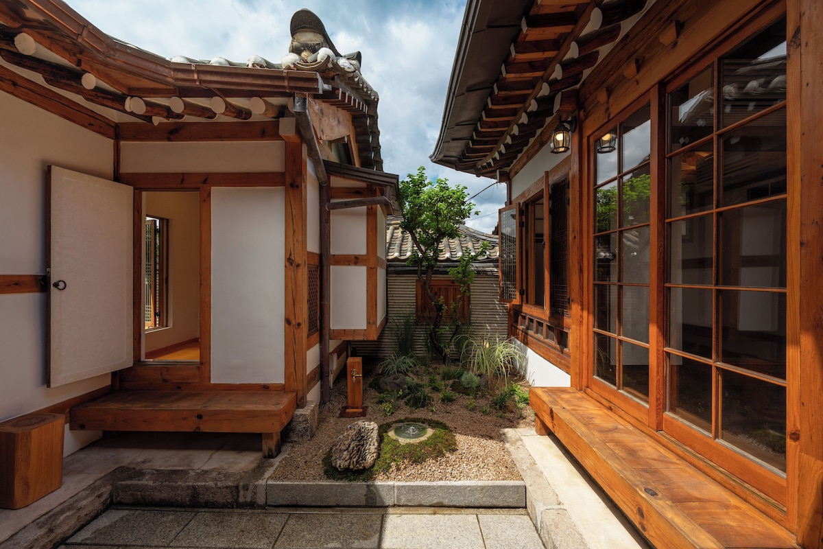 A traditional Japanese building with wooden architecture, a small garden with a stone path, and a wooden door.