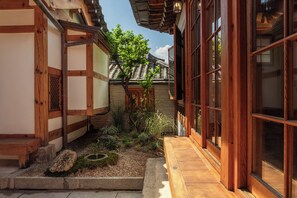 Um edifício tradicional japonês com fachada de madeira, telhado telhado e um jardim com plantas e um pequeno lago.