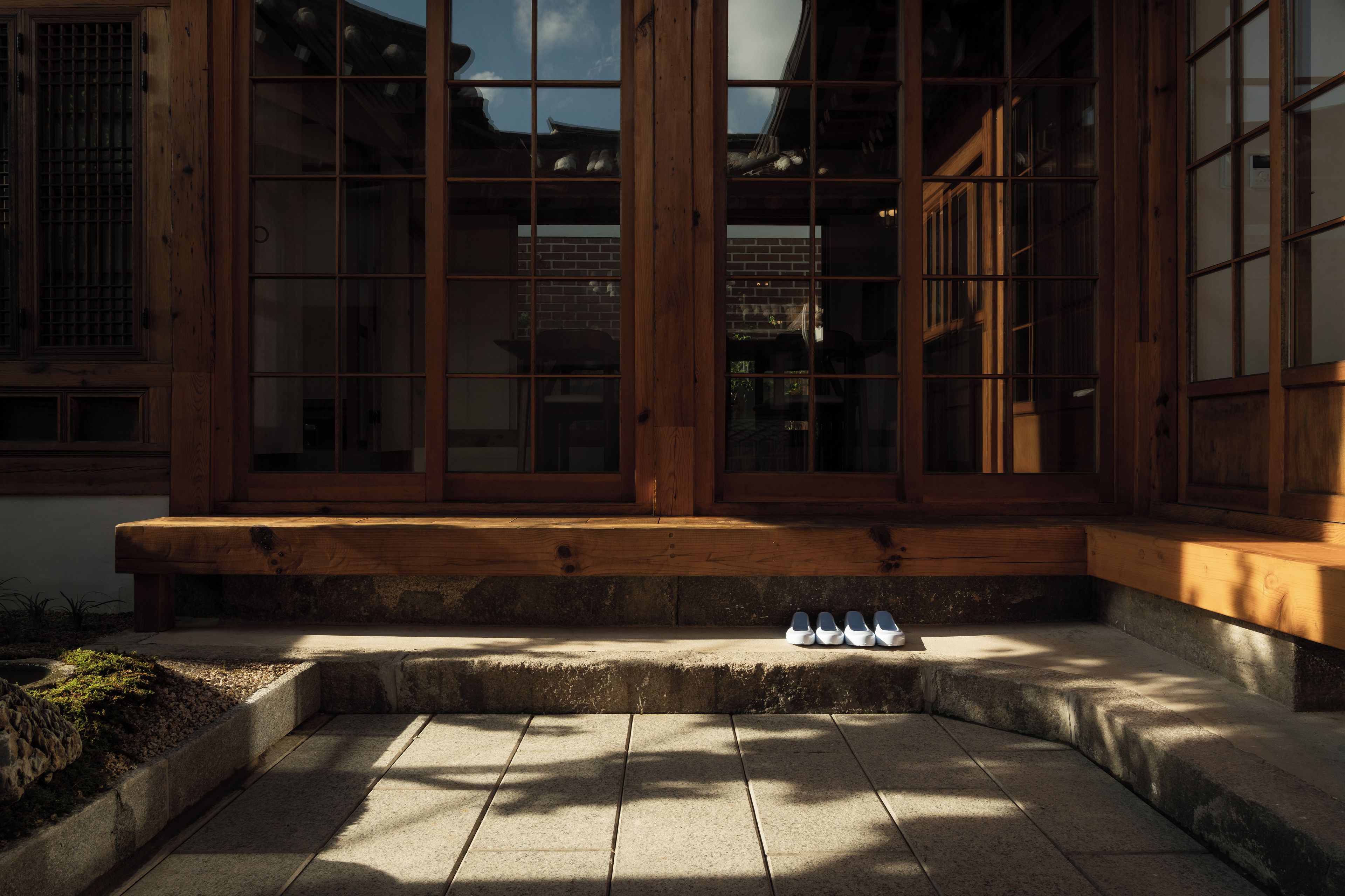A traditional wooden building with large windows and a stone-paved entrance.