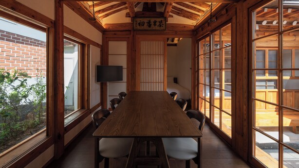 Una habitación tradicional japonesa con suelo de tatami, techo de madera bajo y puertas correderas shoji.