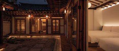 A traditional Japanese-style room with tatami flooring, a low wooden ceiling, and sliding doors.