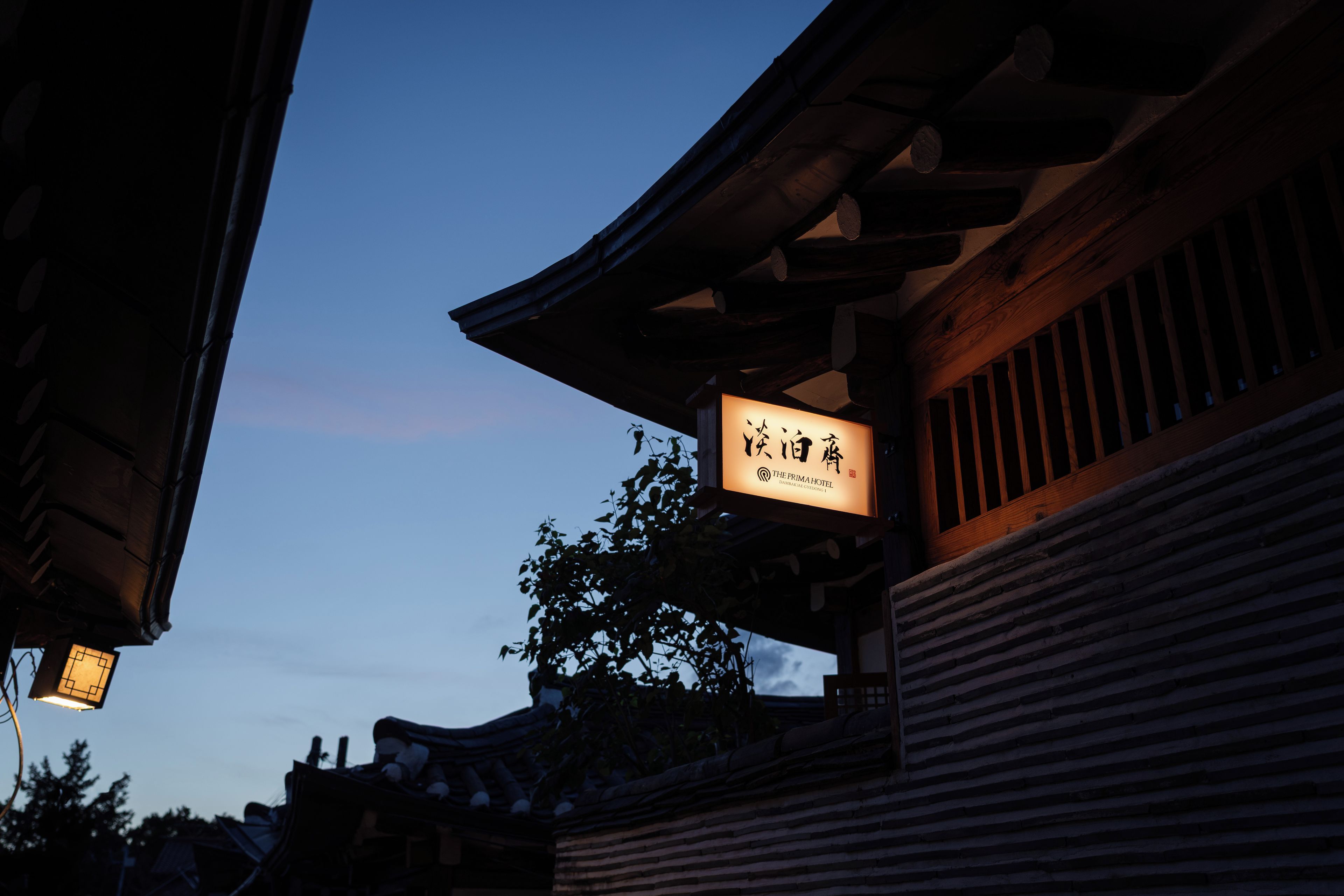 A traditional building with a sign indicating 'The Prima Hotel' and a wooden structure with a sloped roof.