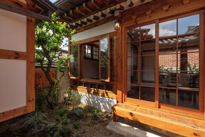 A traditional Japanese-style building with wooden beams, sliding doors, and a small garden area with a bench and plants.