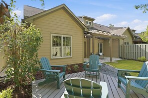 Ein Haus mit einer Terrasse, zwei Stühlen und einem kleinen Garten.