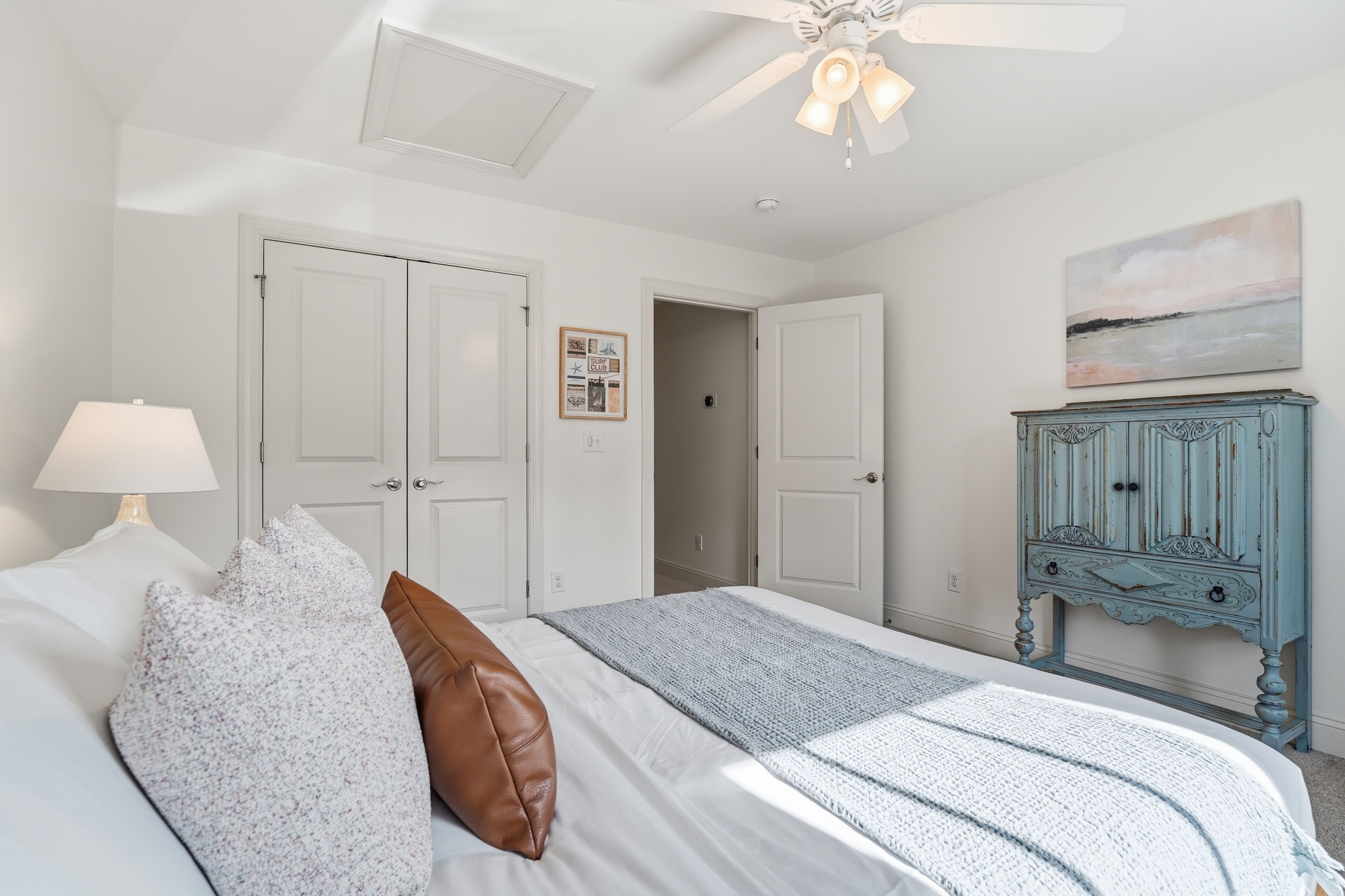 A bedroom with a bed, a nightstand, a ceiling fan, and a dresser.