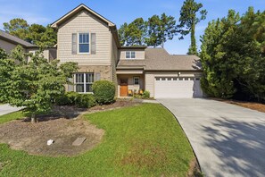 A two-story residential house with a garage, a front yard with a small tree, and a well-maintained lawn. - Cypress Blue - Turo Rental Available (Southern Pines)